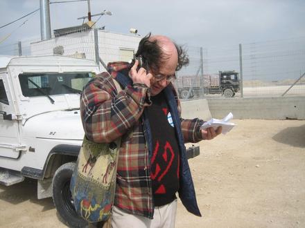 Gush Shalom spokesman Adam Keller speaks with the Palestinian partners on the other side of the terminal