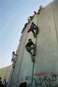 Palestinians climbing to the top of the wall