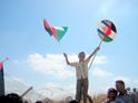 Palestinian boy waving Palestinian flag and the two-flag emblem of Gush Shalom